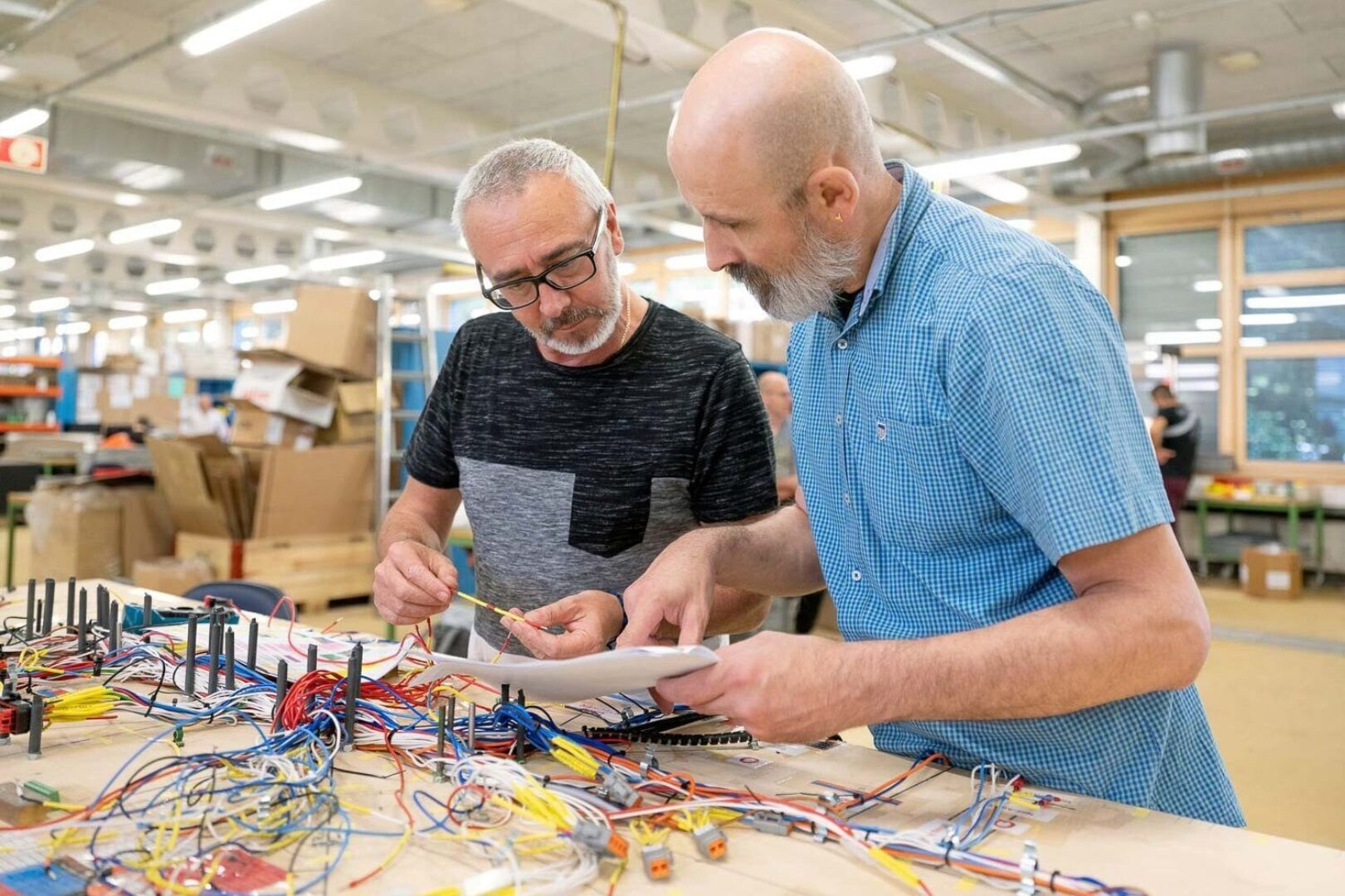 Two men working together on an electronics project in a workshop.