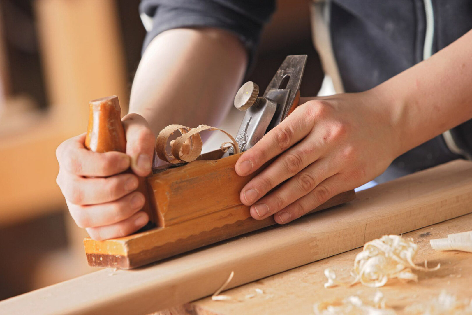 Personen verwenden einen Hobel, um Holz zu bearbeiten.