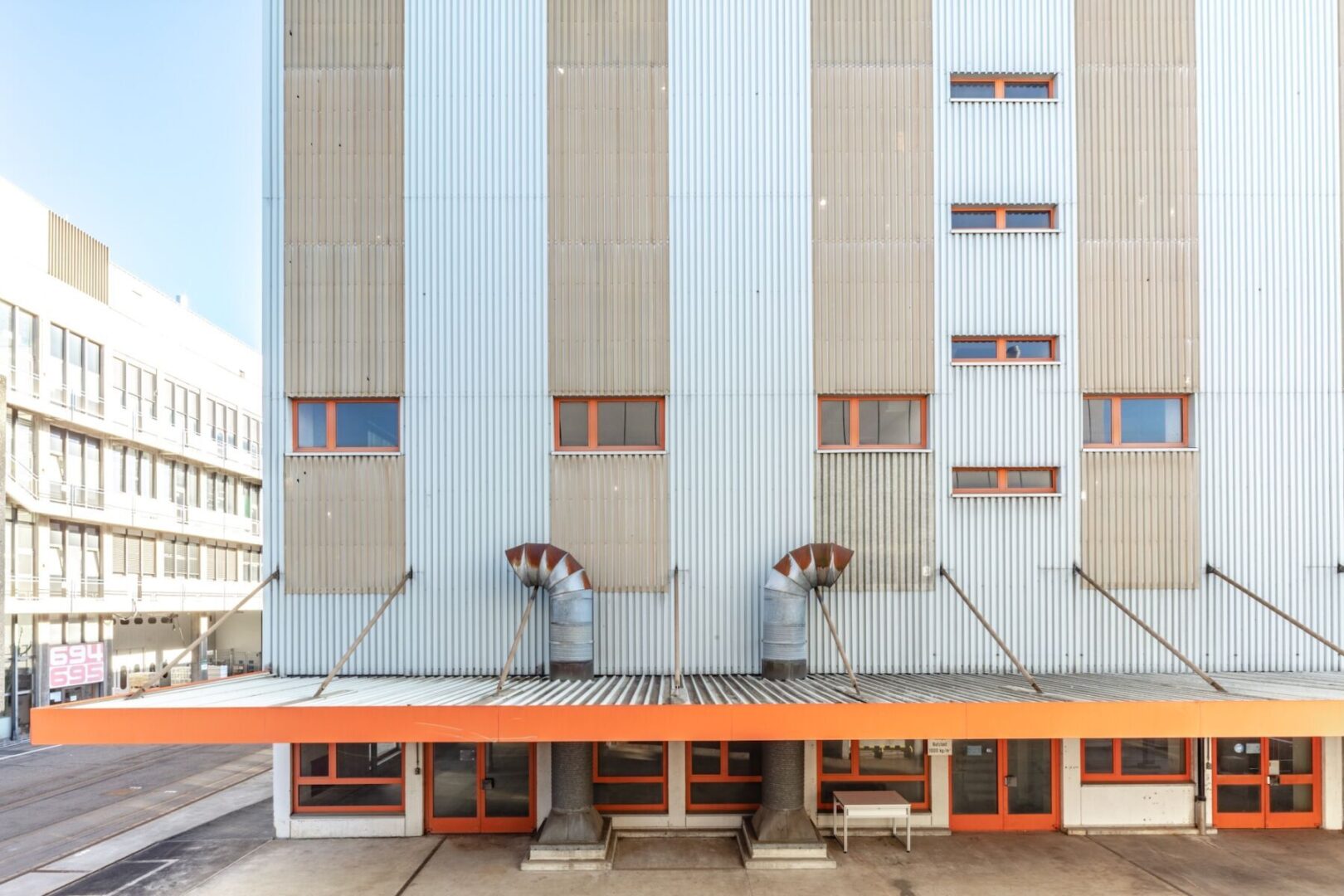 Modern building with corrugated metal facade and orange accents.
