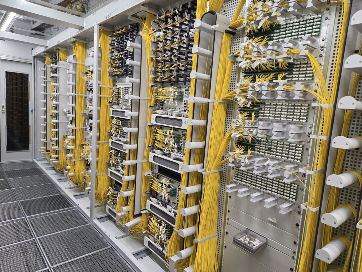 A server room with numerous yellow network cables connected to servers and patch panels.