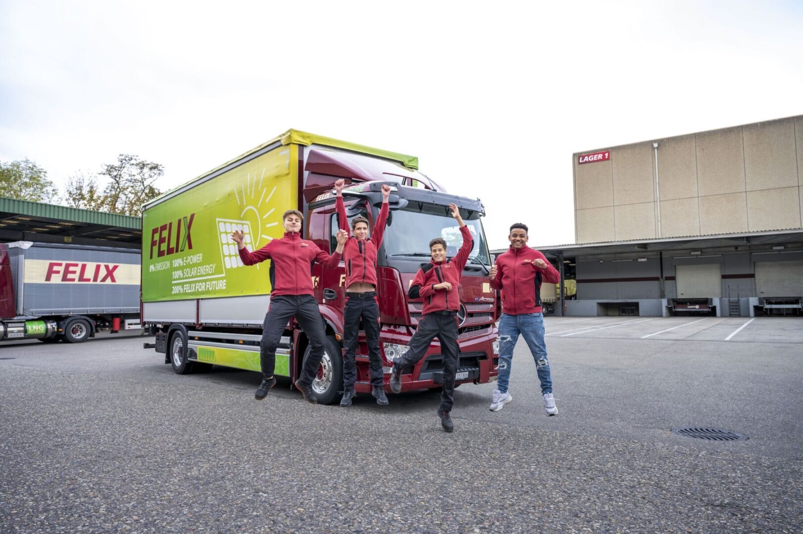 Four people pose cheerfully in front of a large Felix truck in a parking lot.