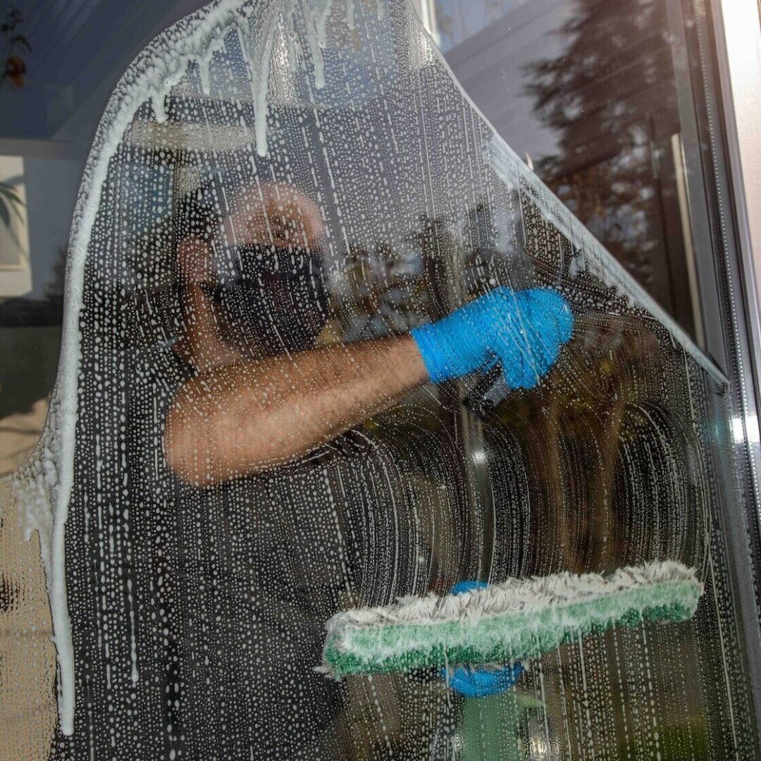 Eine Person wischt ein beschlagenes Fenster mit einem Mikrofasertuch.