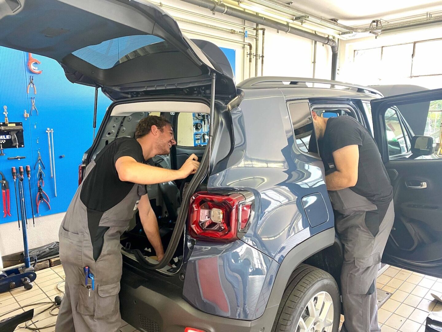 Keigel Werkstatt Mechatroniker Zwei Männer arbeiten an einem Auto in einer Werkstatt.
