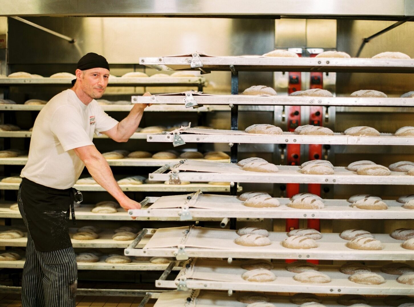 Ein Bäcker in einer Bäckerei mit Brotregalen.
