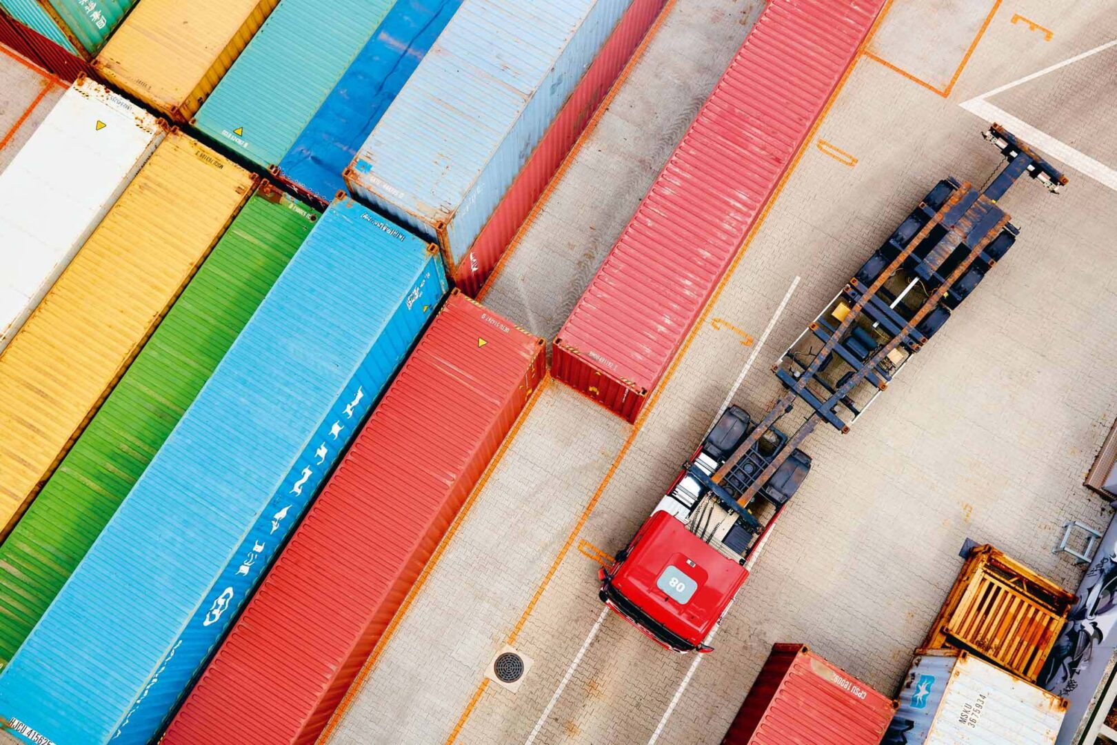 Bunte Frachtcontainer in einem Hafen, gesehen von oben.