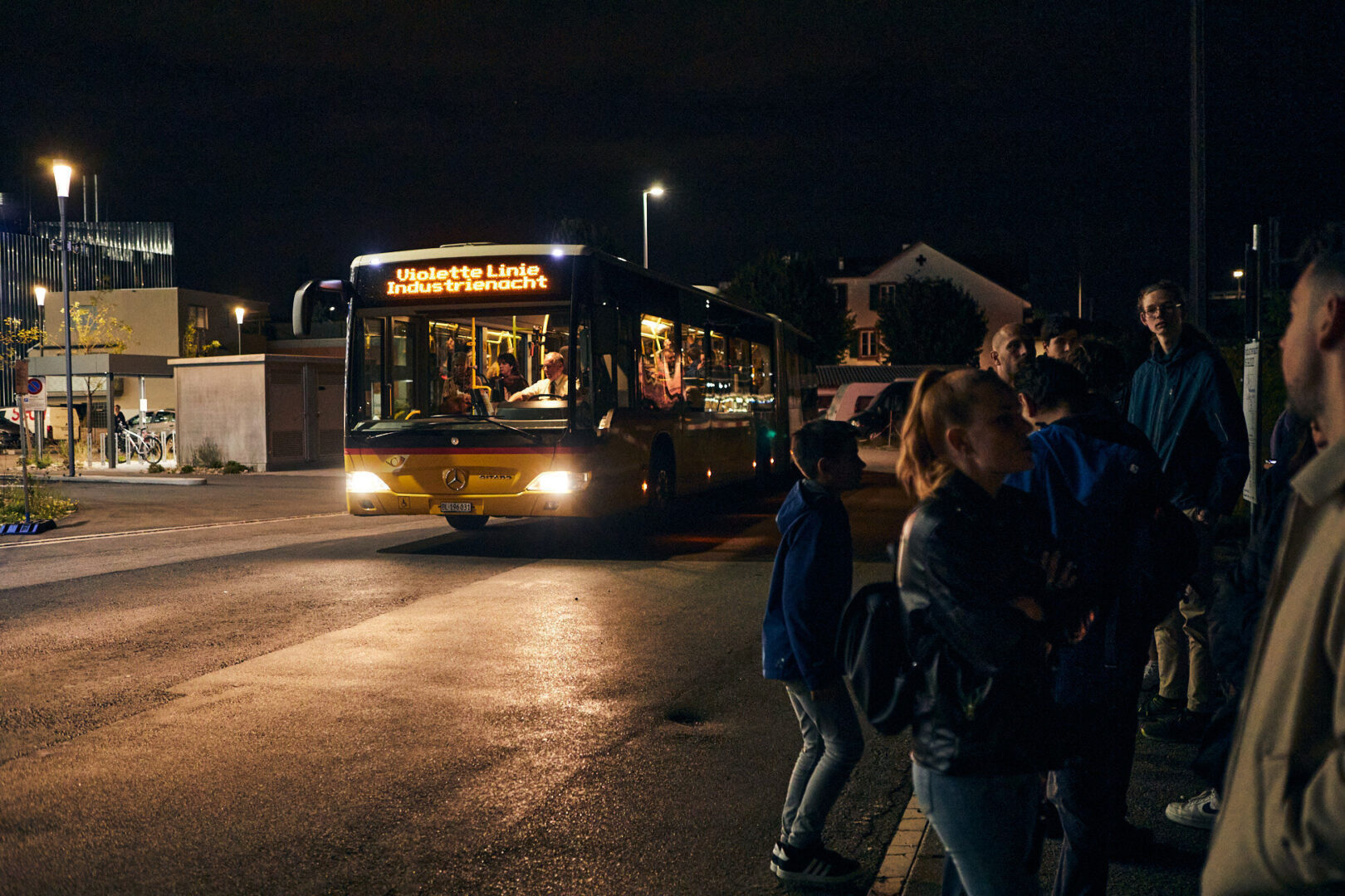 Ein gelber Bus fährt nachts eine Gruppe von Menschen an.