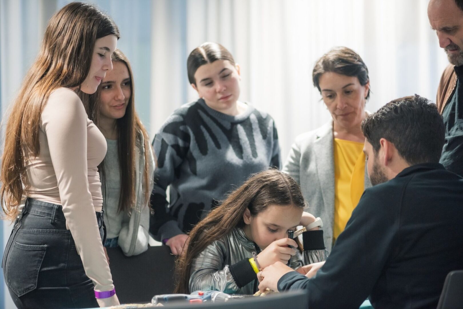 Eine Gruppe von Menschen beobachtet eine Person, die durch ein Mikroskop schaut.