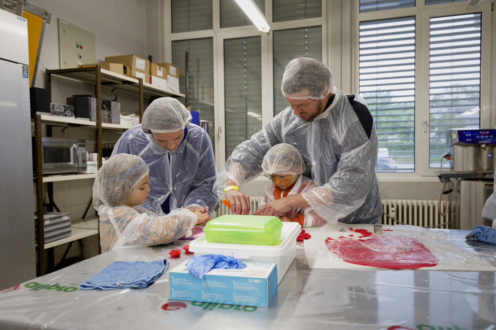 Drei Personen in Schutzausrüstung arbeiten an einem Laboratoriumstisch.