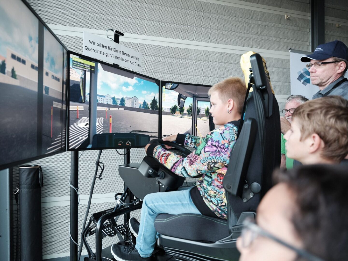 Ein Kind sitzt in einem Fahrsimulator und steuert ein Fahrzeug.
