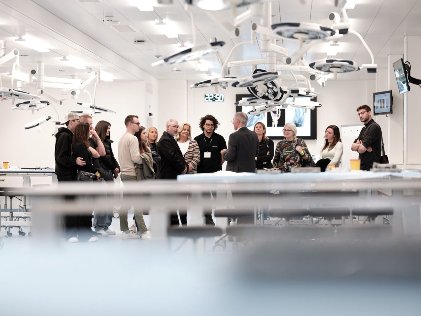 Eine Gruppe von Menschen steht in einem Operationssaal und unterhält sich.