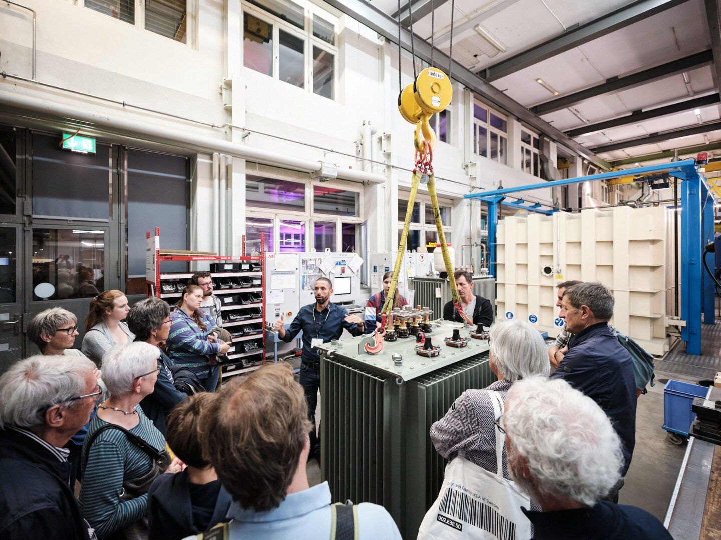 Eine Gruppe von Menschen besucht eine Ausstellung in einer Werkstatt.