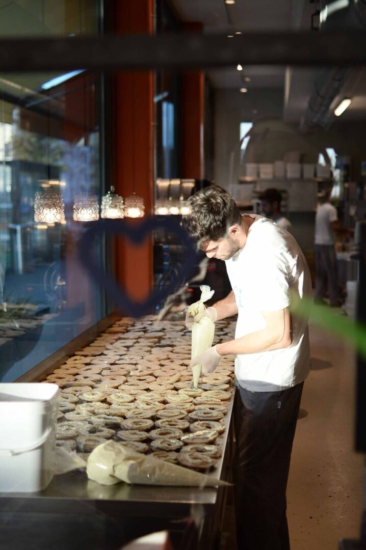 Ein Bäcker füllt Donuts in einer Bäckerei.